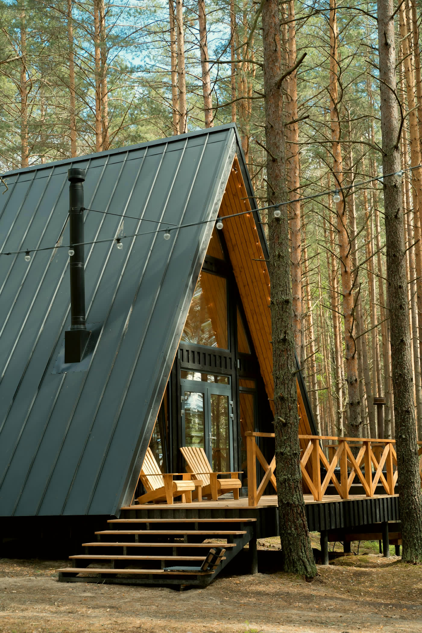 Dark-clad A-frame cabin among tall pines