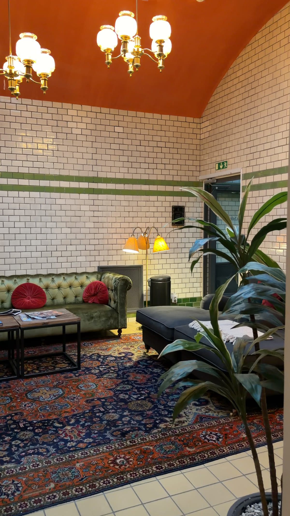 Tiled lounge with a green chesterfield sofa and a patterned rug