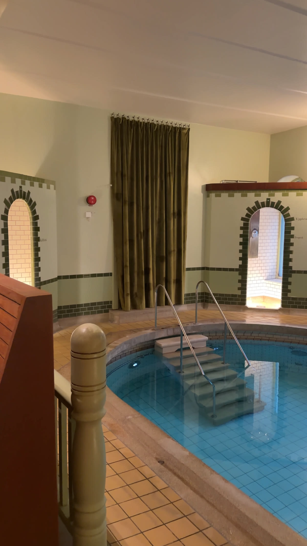 Spa pool with heavy curtains and a tiled alcove beyond