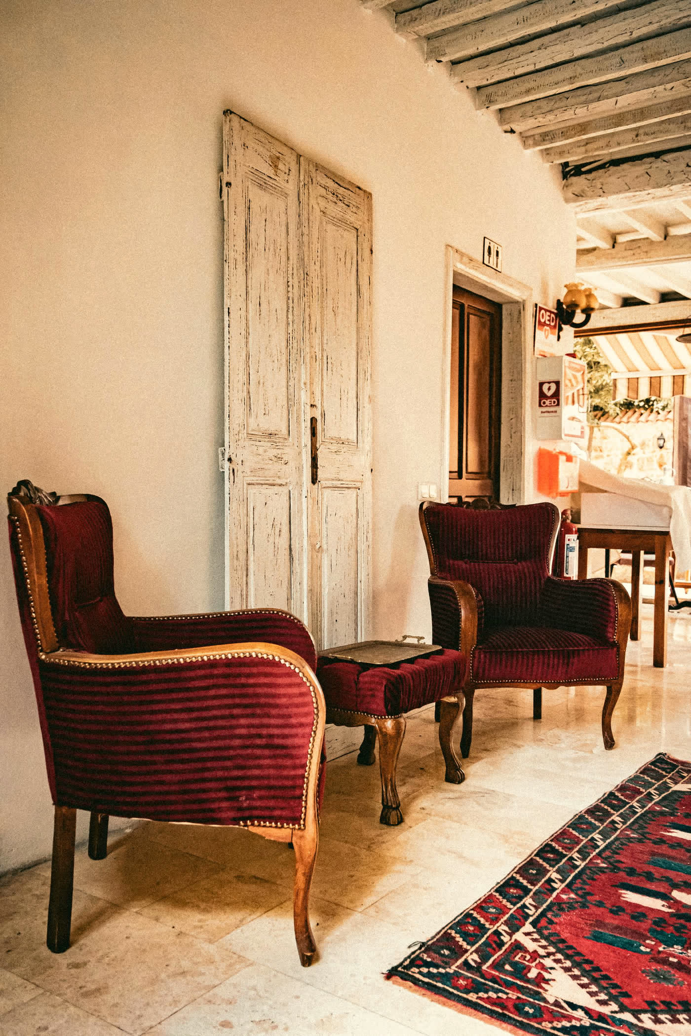 Pair of red velvet armchairs on a patterned rug by weathered doors