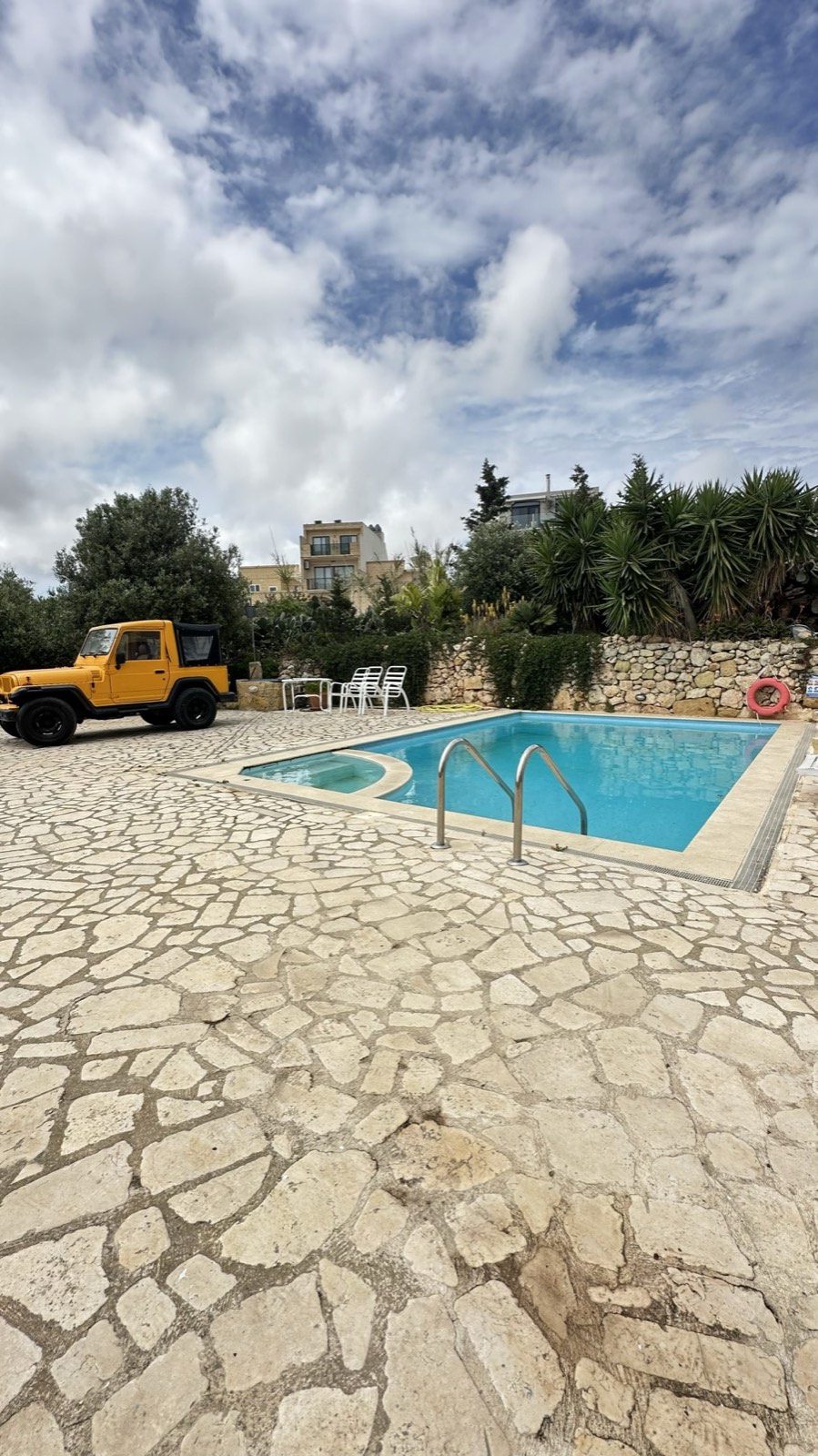 Swimming pool on a stone terrace under a cloudy sky