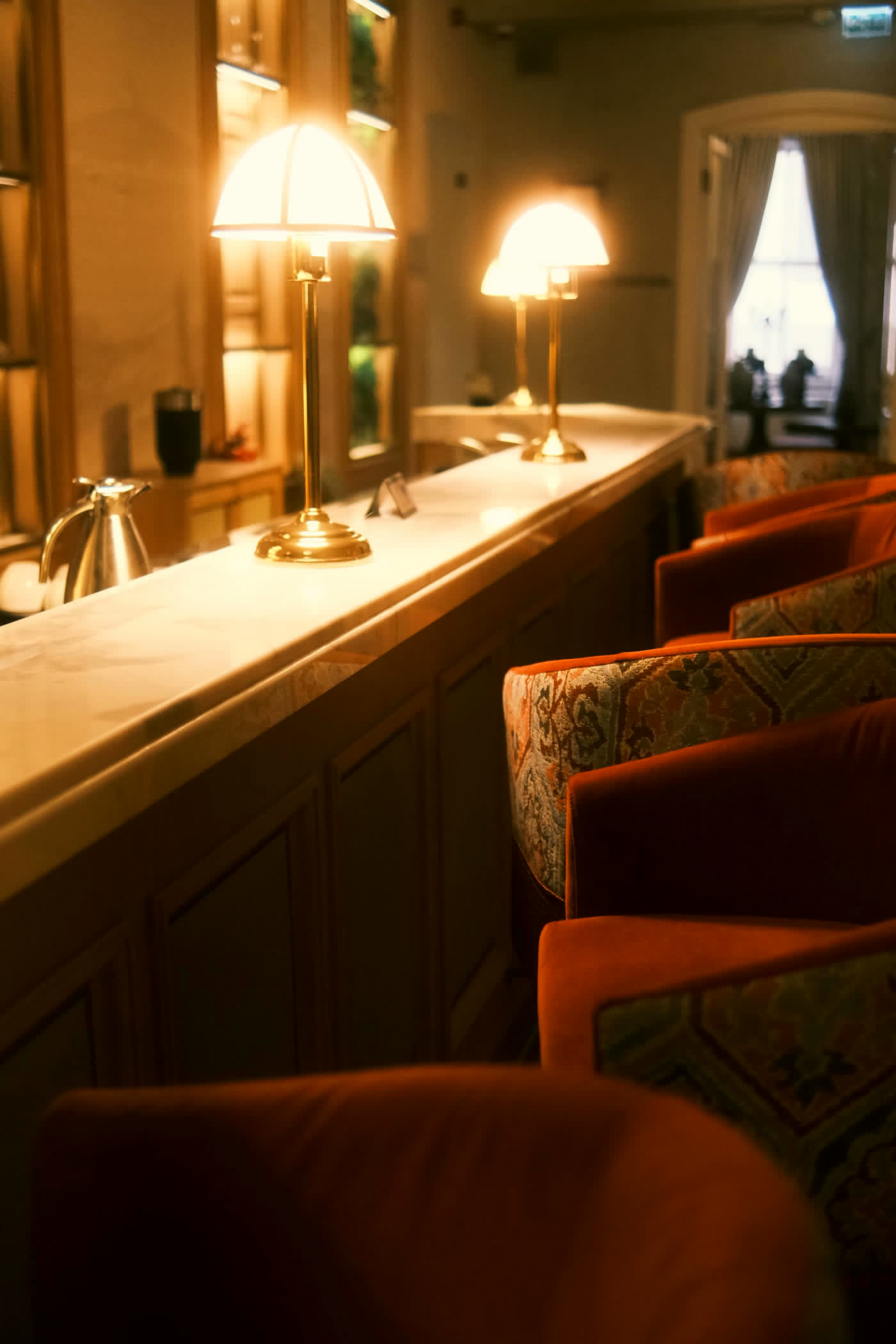 Hotel bar with brass lamps and burnt-orange velvet seating