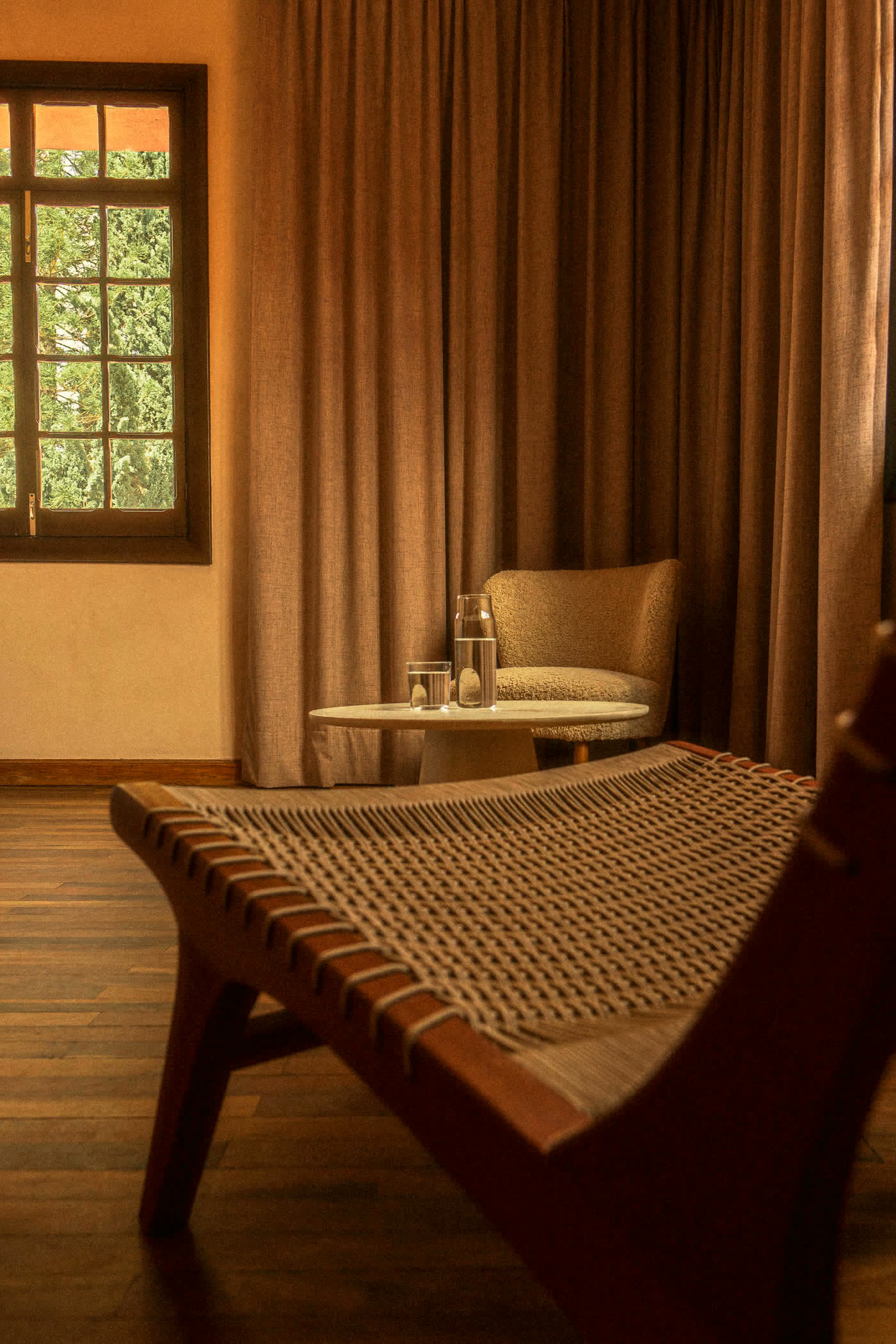 Woven daybed beside floor-length curtains in a warm suite